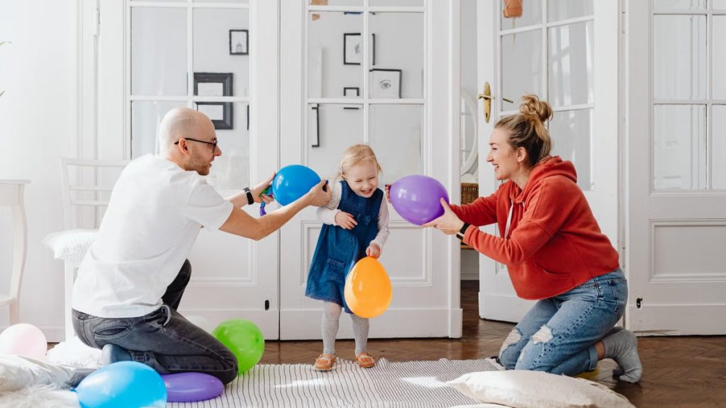 A joyful family playing with colorful balloons indoors, capturing a fun bonding moment.