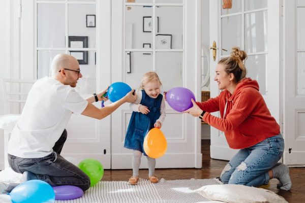 A joyful family playing with colorful balloons indoors, capturing a fun bonding moment.